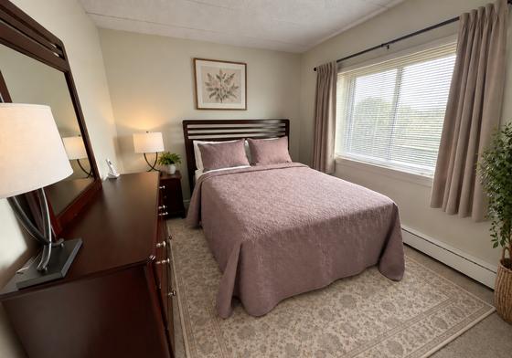 Furnished bedroom with a large window in a J.E. apartment